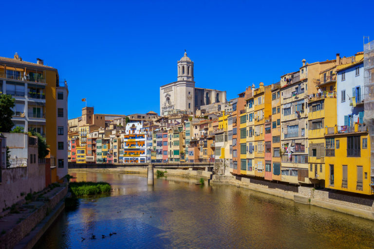 The Onyar River that flows through Girona in Spain with colourful buildings and a blue sky