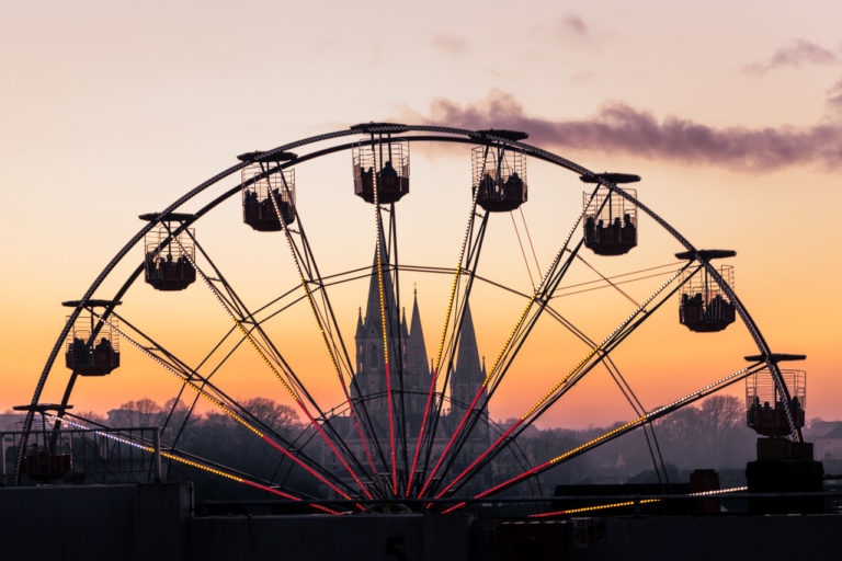 The top half of the Ferris Wheel on Grand Parade with St. Fin Barr's Cathedral in the background and the sky is a lovely orange and purple