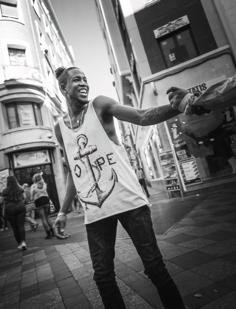 A man wearing a tshirt with "HOPE" and a ship's anchor on it is laughing and grabbing the arm of someone off camera.