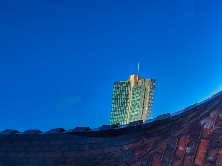 The Elysian building reflected in a car window with a wall at the bottom of the window.