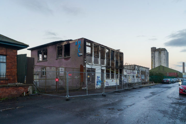 A burnt out building surrounded by fencing.