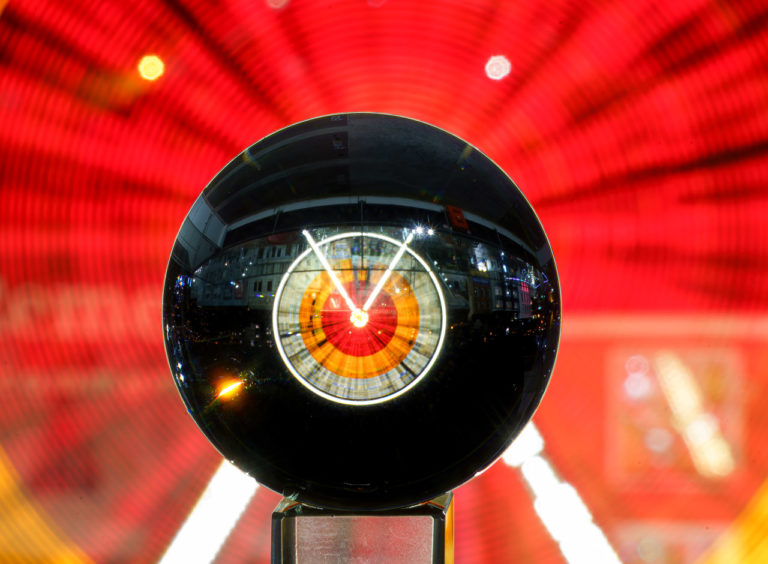 A close up of a glass ball through which a ferris wheel is seen, upside down.