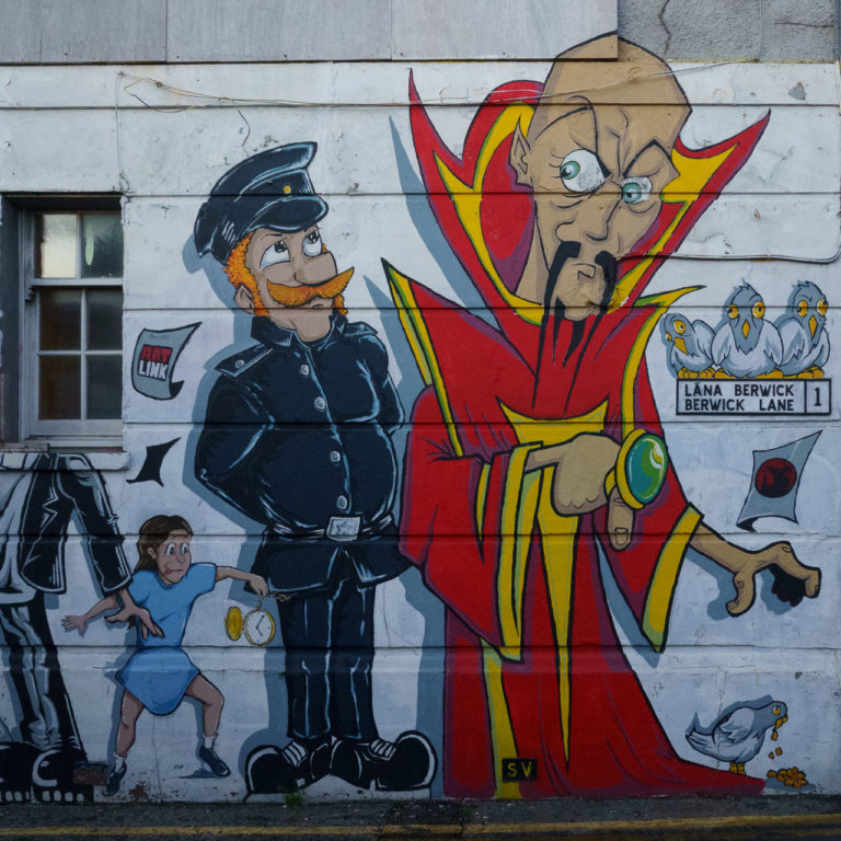 Ming The Merciless, a policeman and a child drawn on the wall of a building.