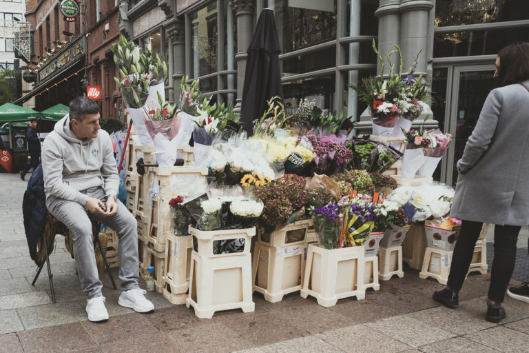 A man selling flowers on Graft Street watches as a woman looks for what she wants to buy