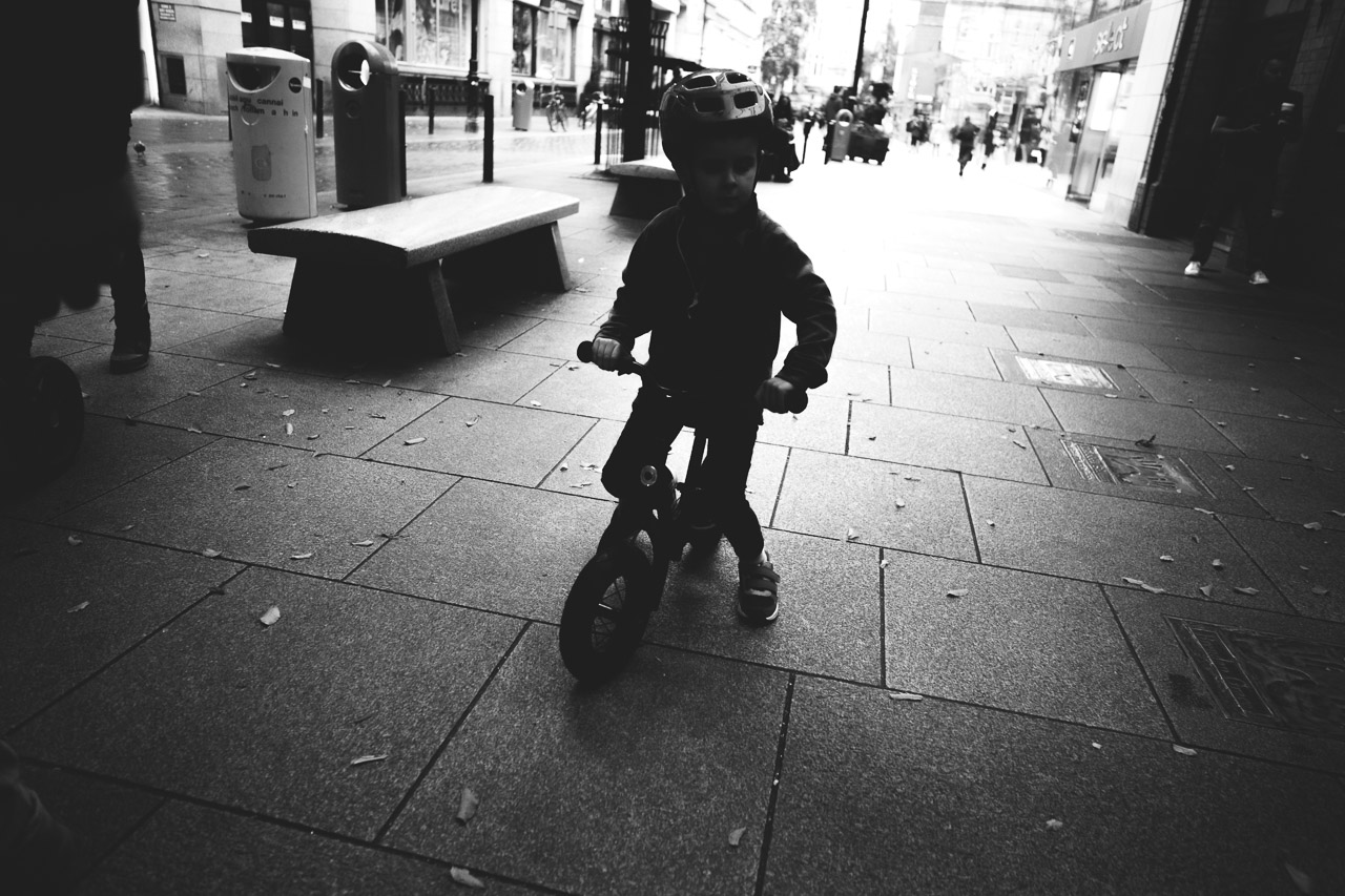 A boy on his training bike in the shadows cast by the Gaiety Theatre entrance.