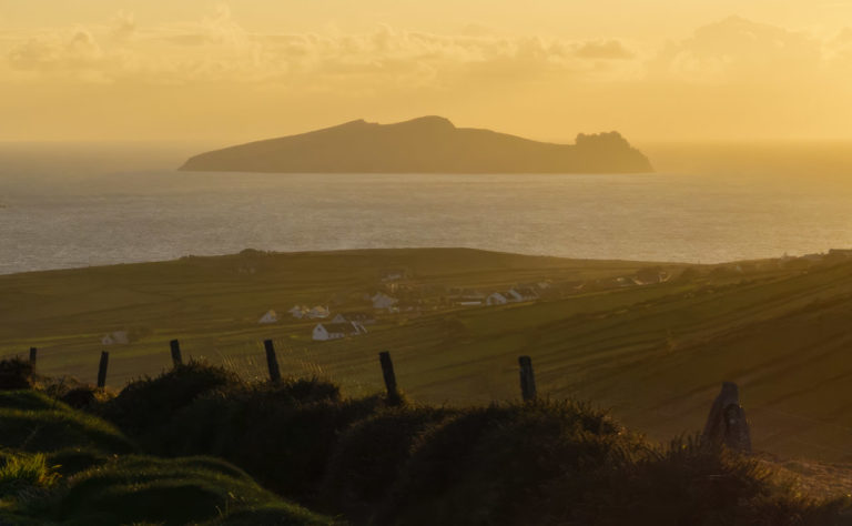 The island known as "An Fear Marbh" or "Inis Tuaisceart" lies off the coast of Kerry. The sun is setting, casting a lovely glow over everything.