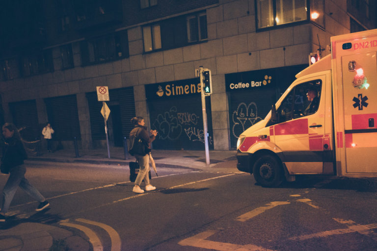 A woman crossing the road waves nervously at an ambulance that went through a red light to an emergency
