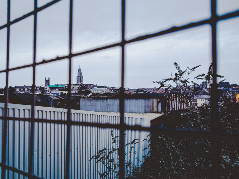Part of Cork City seen from behind the fence of a car park.
