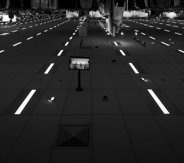 An inverted photo showing the ceiling of a shop. Inset lights lead the eye into the distance.