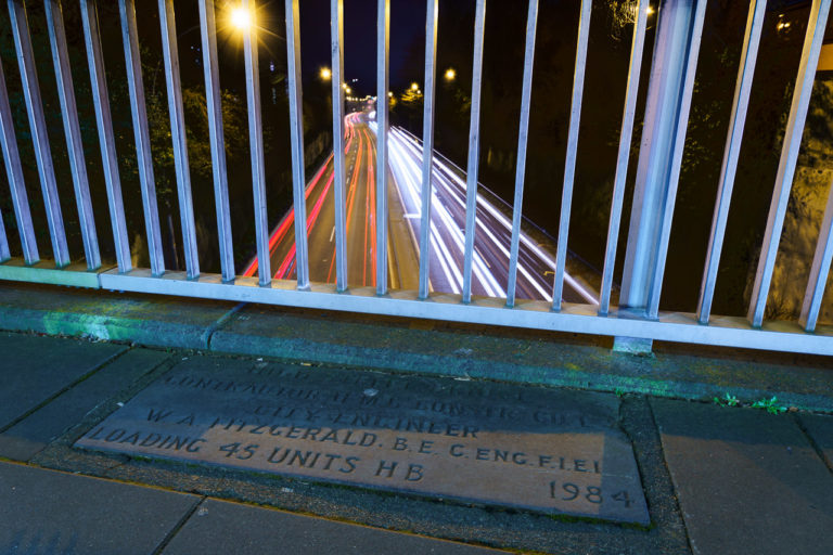 Red and white light trails of passing cars under the High Street Bridge in Cork.