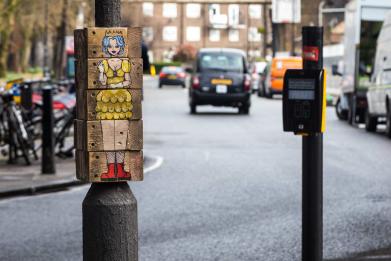 A picture of a princess made from blocks on a pole on a street. A taxi can be seen in the background.
