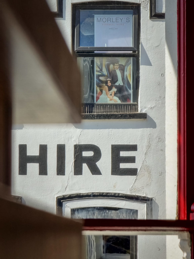 A detail from the building of Morley's Suit Hire on Daunt Square in Cork. It's shot from inside the McDonalds across the Square so the frame of the window is visible
