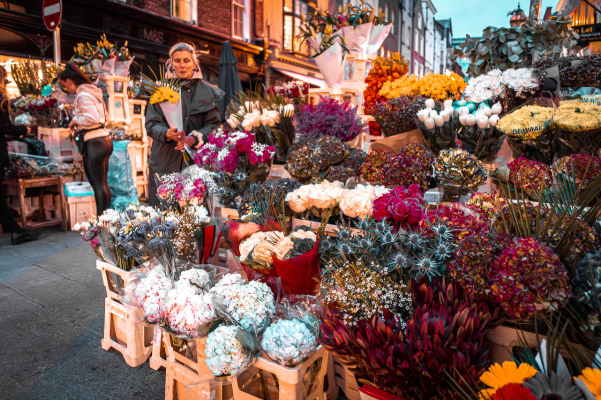 A woman clutches a bouguet of flowers next to a large display of flowers for sale on Grafton Street in Dublin.