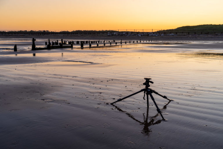 A tripod on the beach at sunset