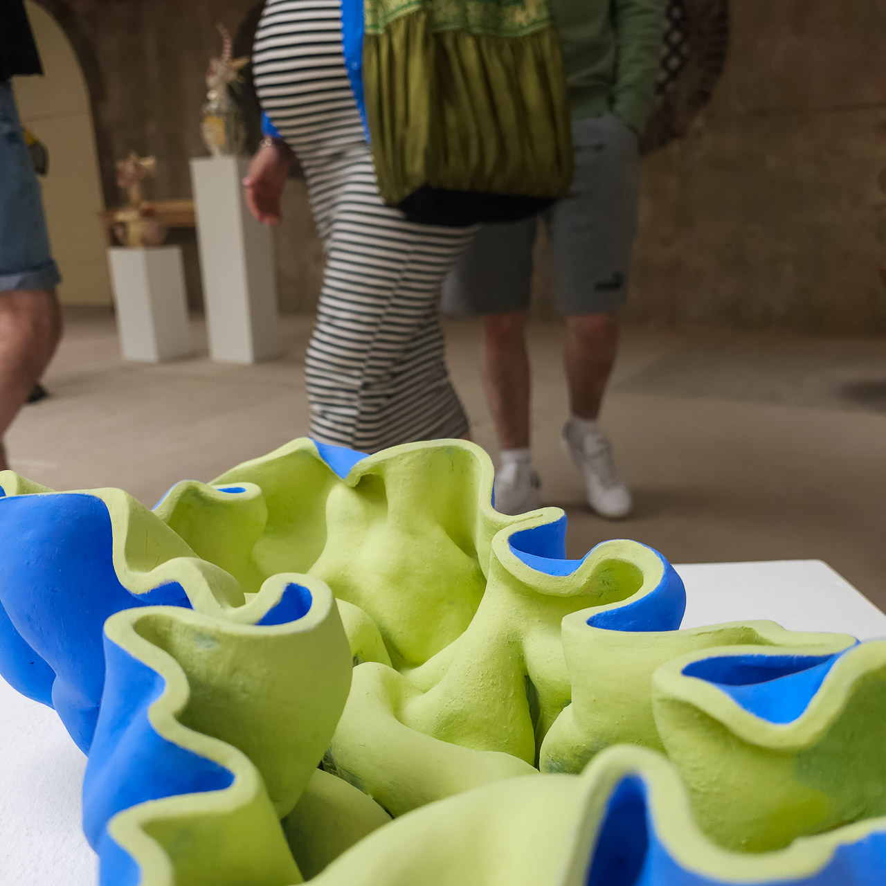 A woman walks past a blue and green art piece.