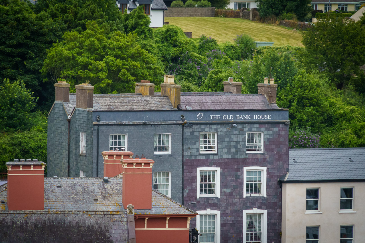 The top of the Old Bank House and other buildings in Kinsale and the green fields, trees and houses behind.