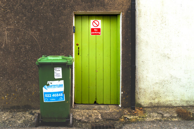 A green door and a wheelie bin. A No Parking sign on the door and the wheelie bin comes from Country Clean.