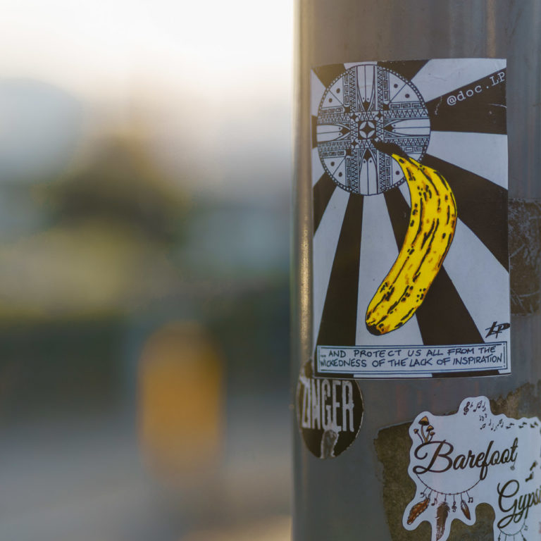 A sticker on a poll shows a banana, a black and white design and the phrase, "... AND PROTECT US ALL FROM THE WIKDEDNESS OF THE LACK OF INSPIRATION"
