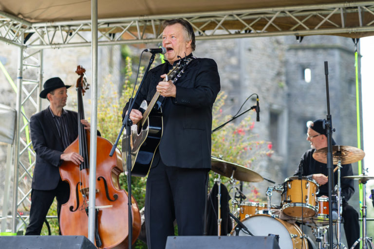 The Strictly Cash tribute band on stage. a double bass player and drummer in the background while the singer plays his guitar and sings