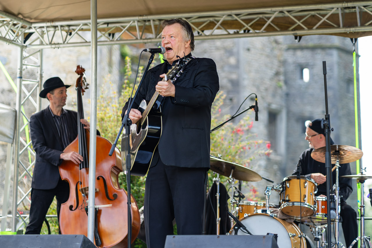 The Strictly Cash tribute band on stage. a double bass player and drummer in the background while the singer plays his guitar and sings