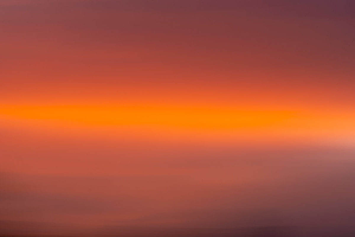 The colours of a sunset captured in the sweep of an ICM photo. Dark to bright orange and a bit of dark at the bottom where the roof of a house was.