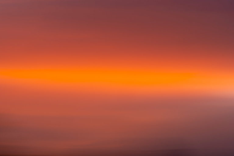 The colours of a sunset captured in the sweep of an ICM photo. Dark to bright orange and a bit of dark at the bottom where the roof of a house was.