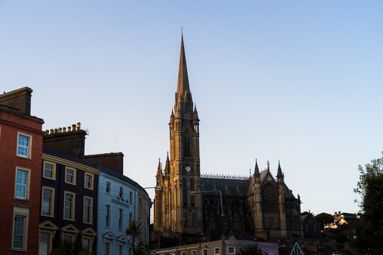 Cobh Cathedral overlooks the town. Some houses visible on the left and a clear blue sky overhead.