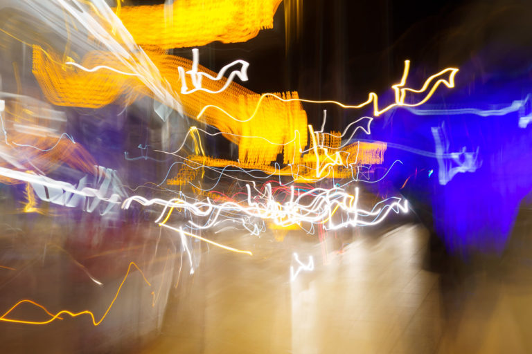 A long exposure photo of a street with a passing bus that says, "Culture Night" on the front captured in maddening, disorganising streaks of colour.
