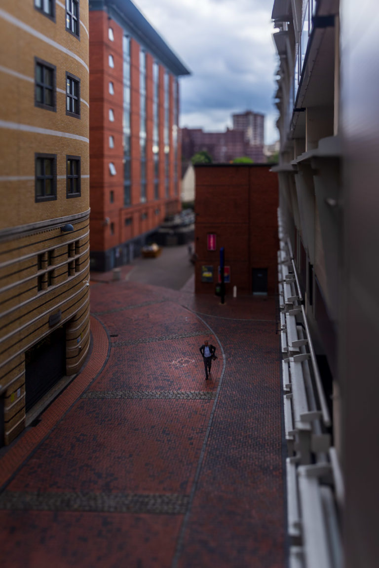 A man in a suit walks between tall buildings in Birmingham