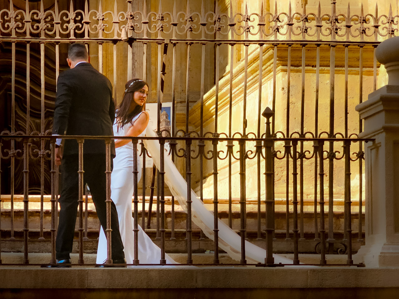 A couple walk along a raised platform outside Malaga Cathedral.