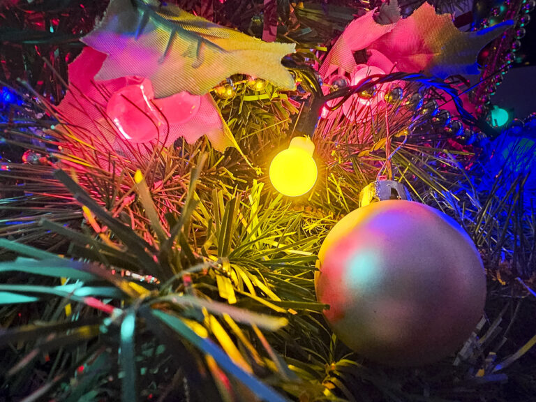 A glowing yellow light brightens a Christmas tree, surrounded by decorations.