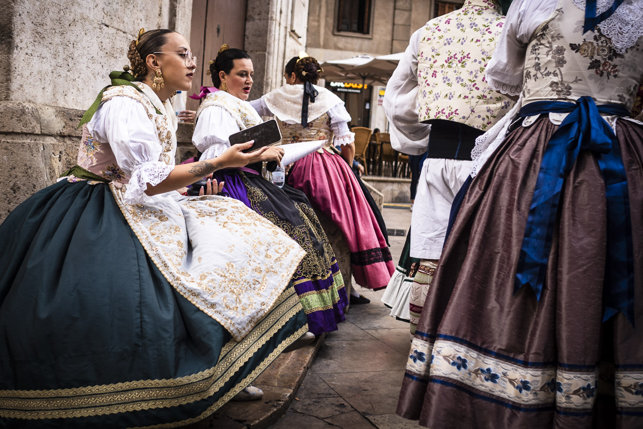 Women dressed in large, billowing, brightly lit dresses with the one in the foreground holding her phone.