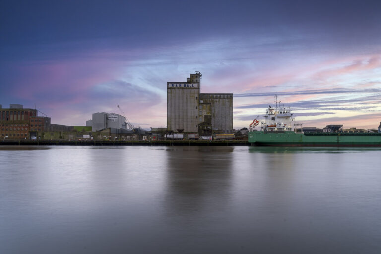 The R&H Hall building in the centre of an image showing Kennedy Quay in Cork. A ship is docked on the quay. Southern Milling Ltd have a smaller building nearby and the old Odlums, red-bricked, building is visible to the far left.