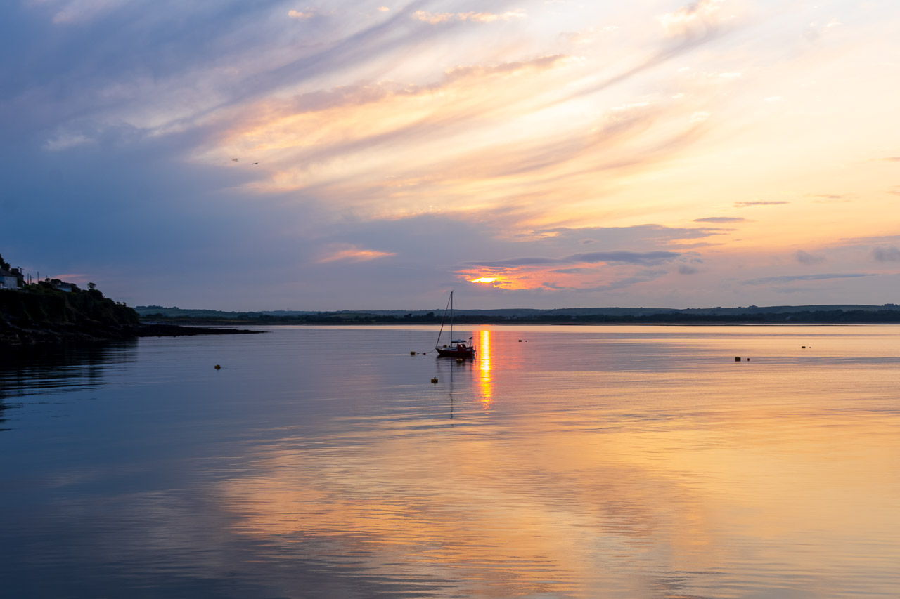Small boat on the water outside Ballycotton harbour as the sun sets behind.
