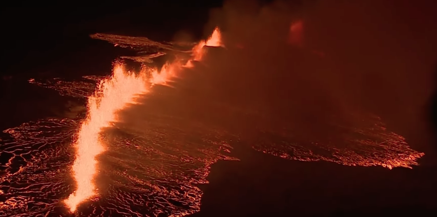 An erupting volcanic fissure with lava spewing out of it.