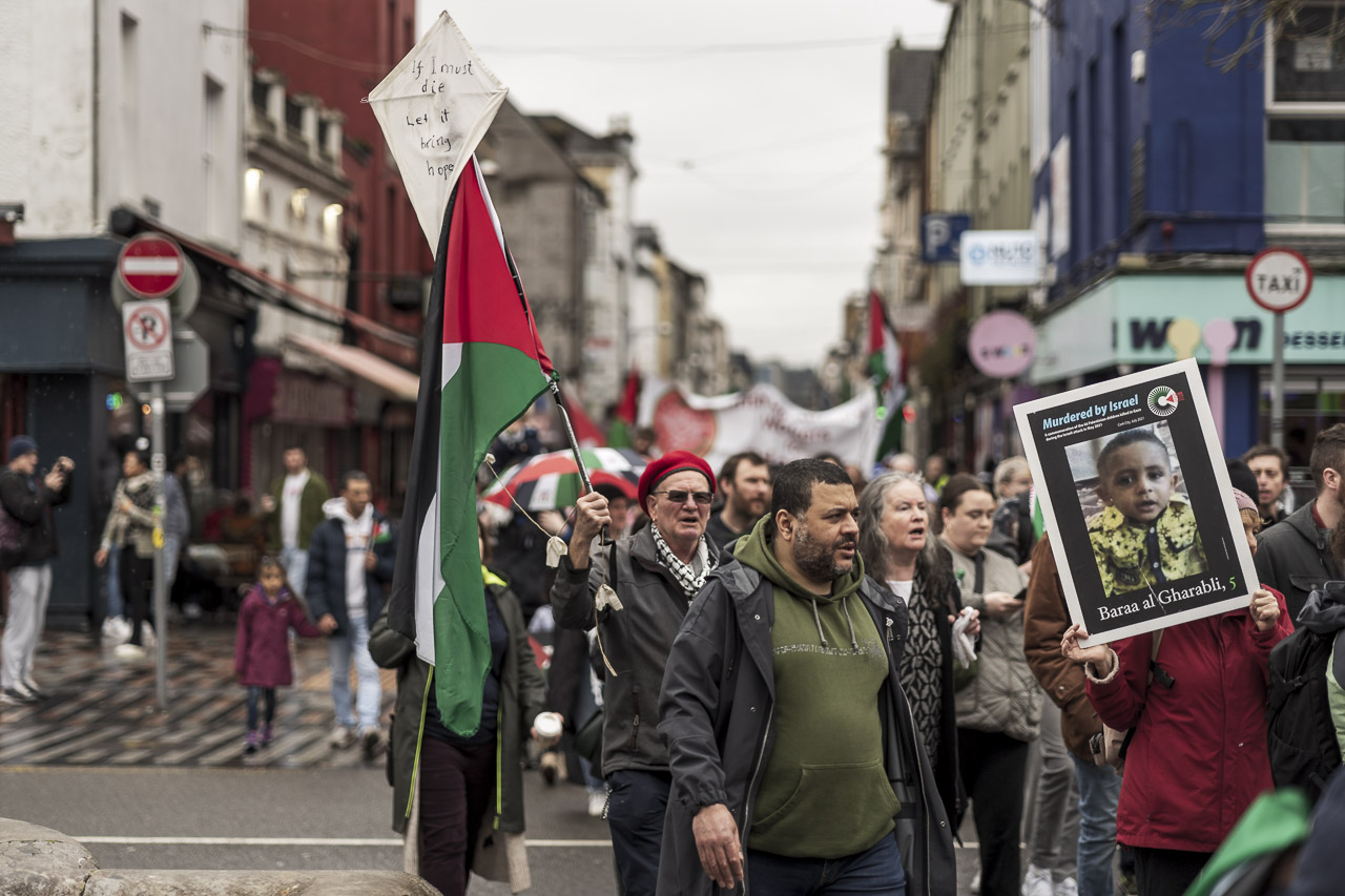 People walking in a rally in support of Gaza. Some carry posters and flags.