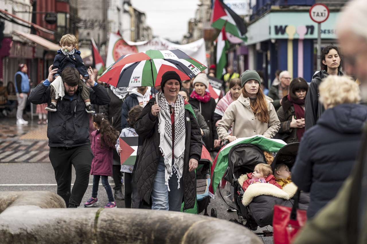 People walking in a rally in support of Gaza. Some carry posters and flags.