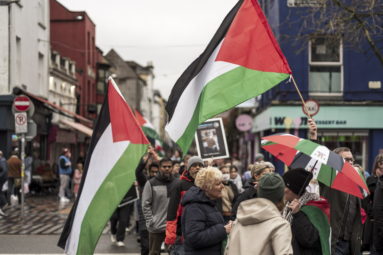 People walking in a rally in support of Gaza. Some carry posters and flags.