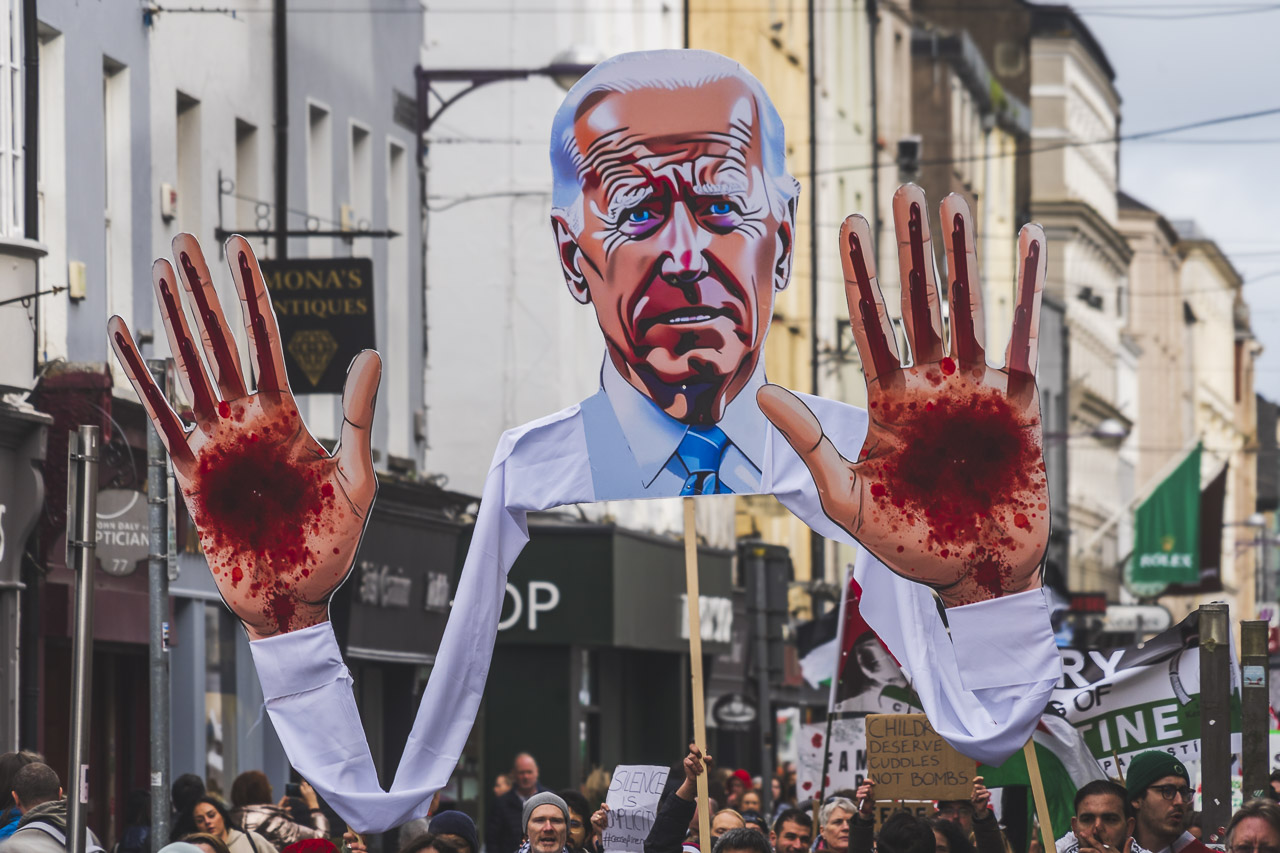 A huge likeness of US President Biden with blood spattered hands held aloft by members of the rally.