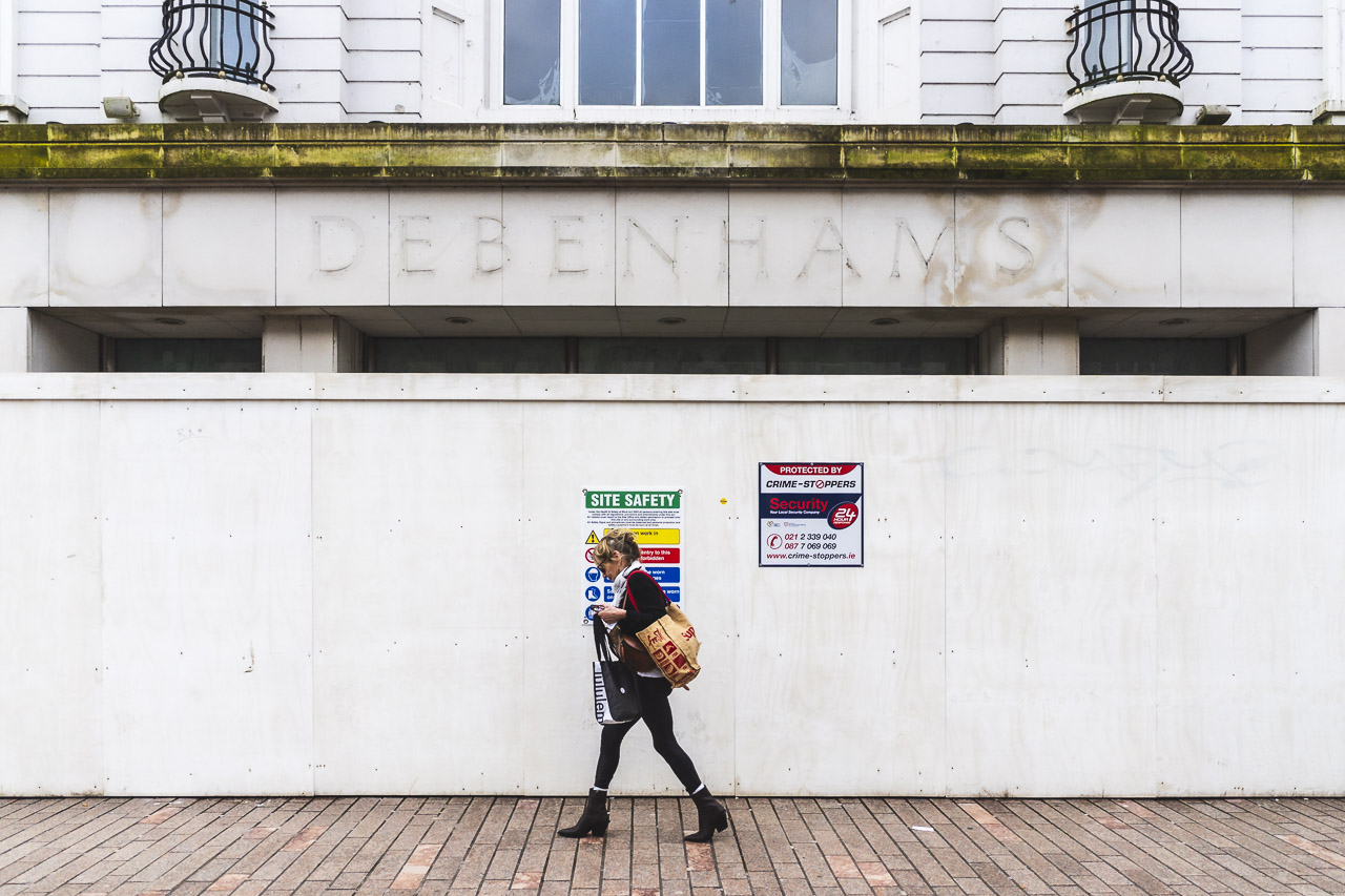 A woman walks past the front entrance of the old Roches Stores, or later Debenhams, but now a derelict building in the heart of the city.
The building is surrounded by hoarding.