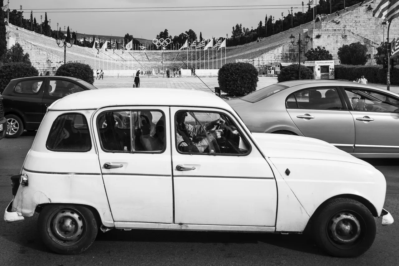 Cars drive slowly past in a traffic jam outside the Panathenaic Stadium in Athens, Greece.
An old Renault 4 is seen in the foreground.