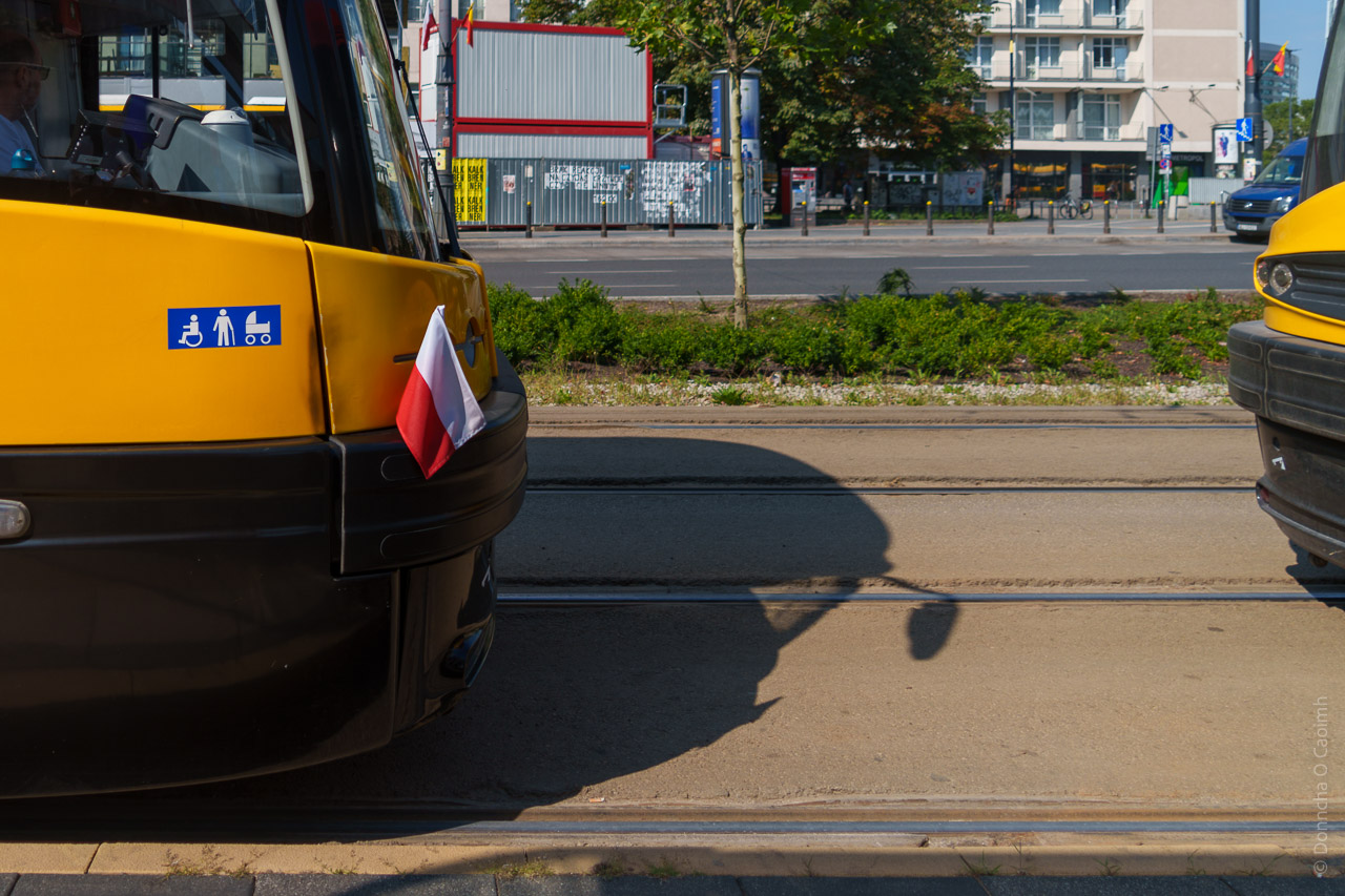 A tram on the street with a little Polish flag stuck in the bumper.