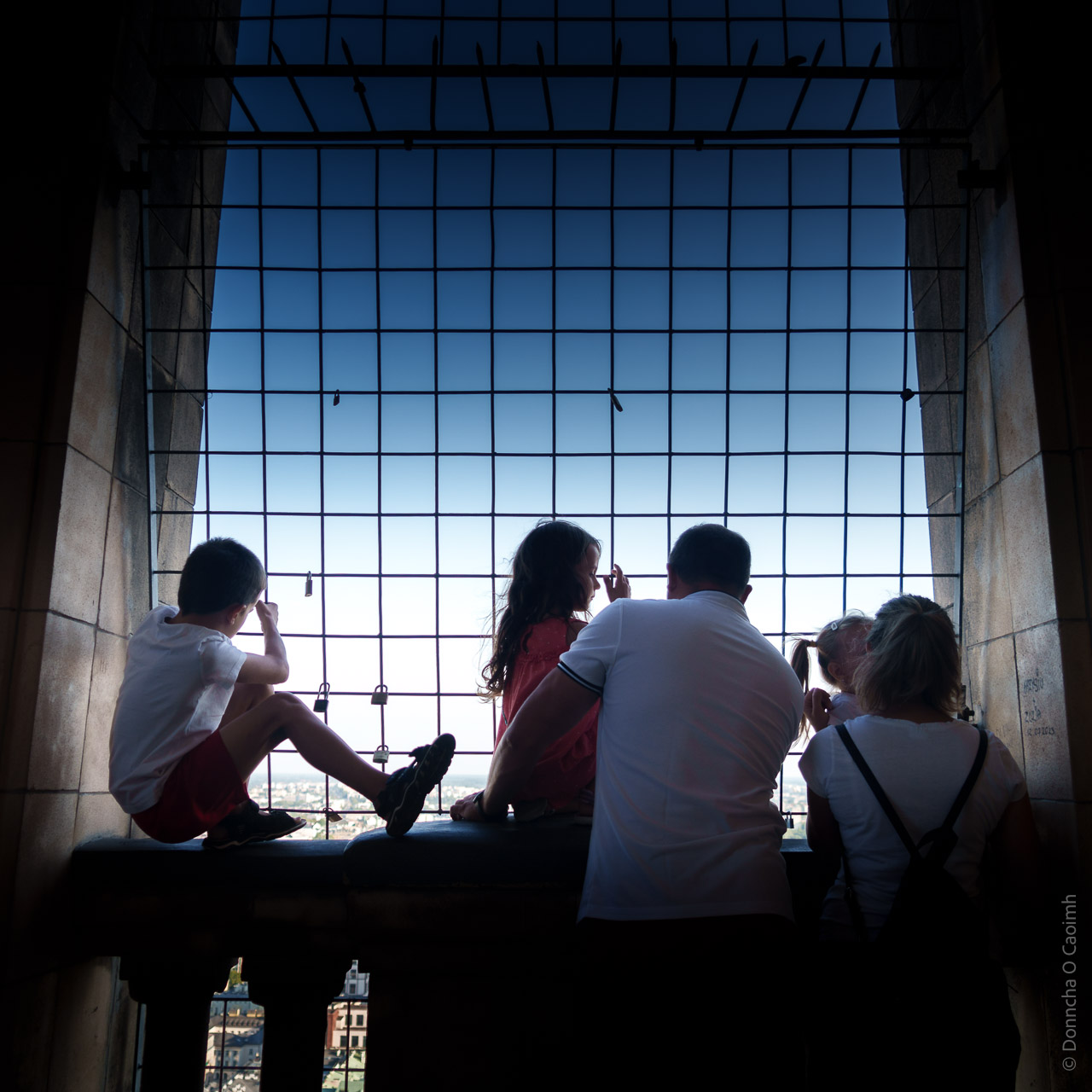 A family looks out on Warsaw through a barred window in the Palace of Culture and Science.
Parents, 2 daughters and a son are pictured.