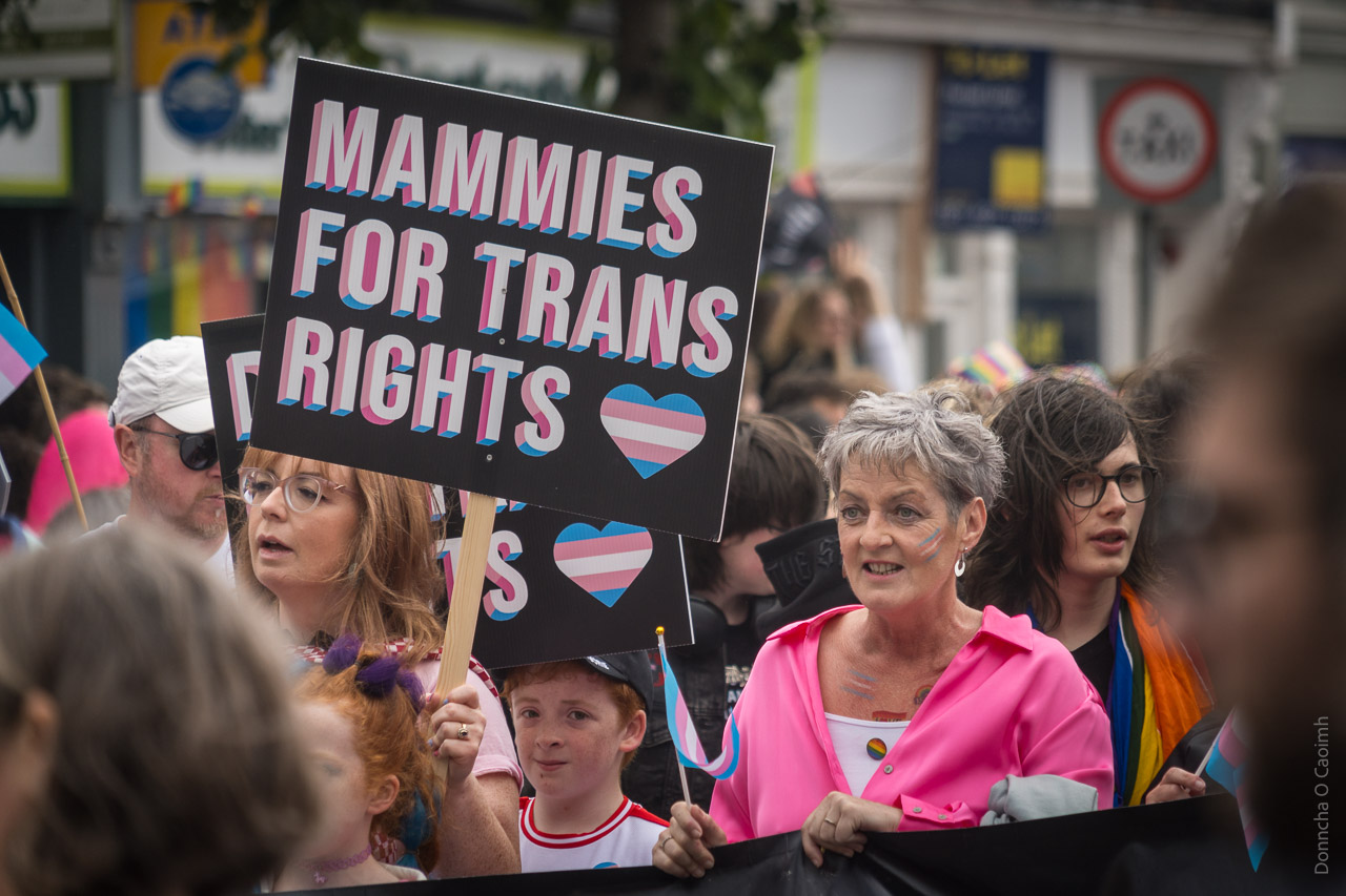 A woman holds a sign saying, "MAMMIES FOR TRANS RIGHTS"