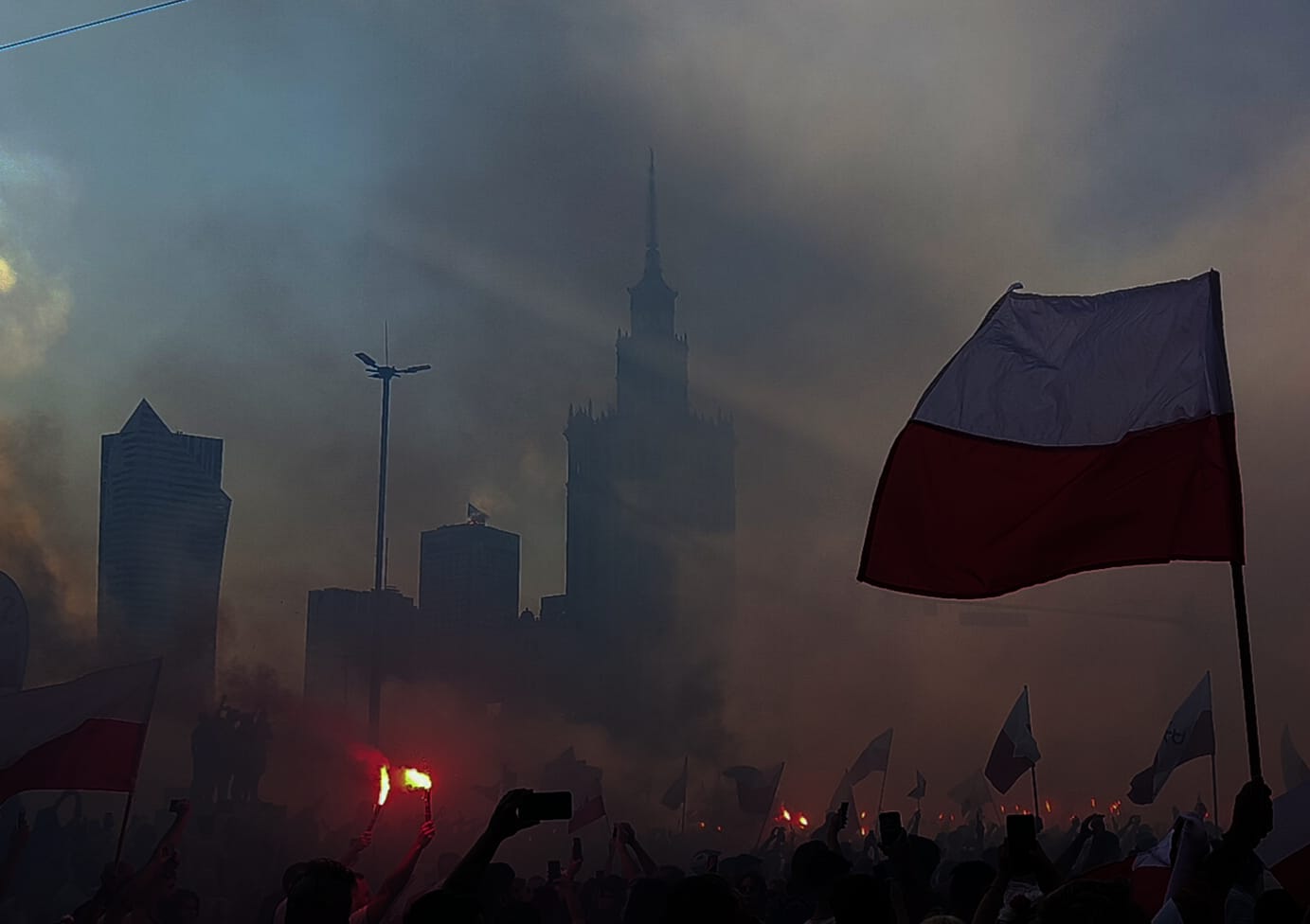 Polish flags fly as they are surrounded by smoke from flares