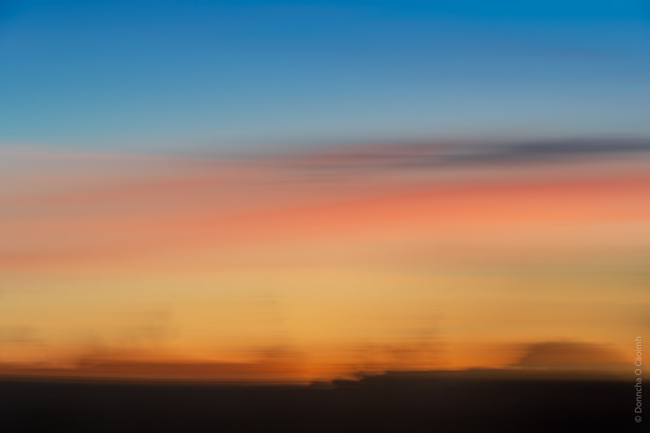 The blue, orange, yellow, red and shadows of the sunset blur together.
