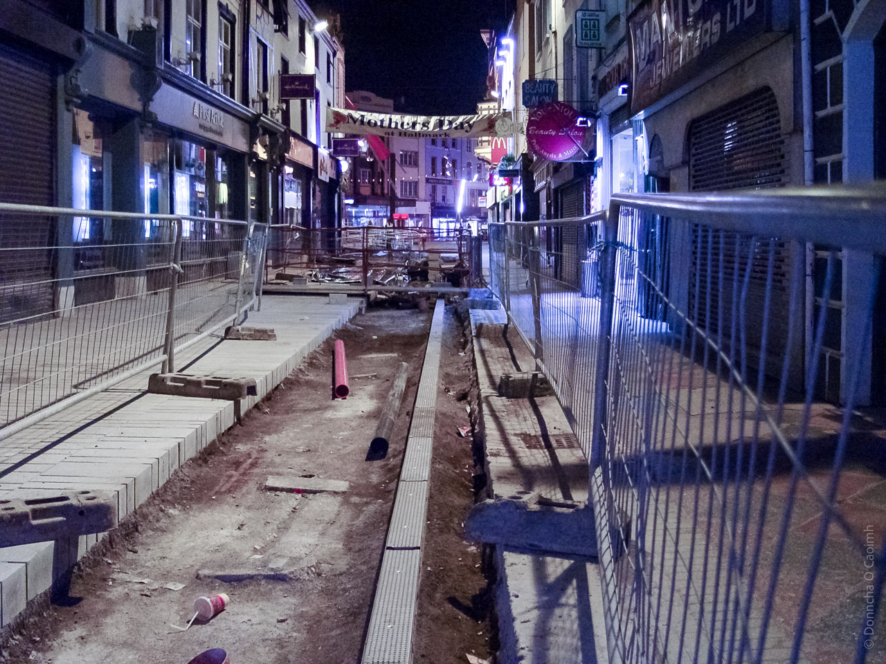 A construction site in a city, with the middle of a paved road dug up.