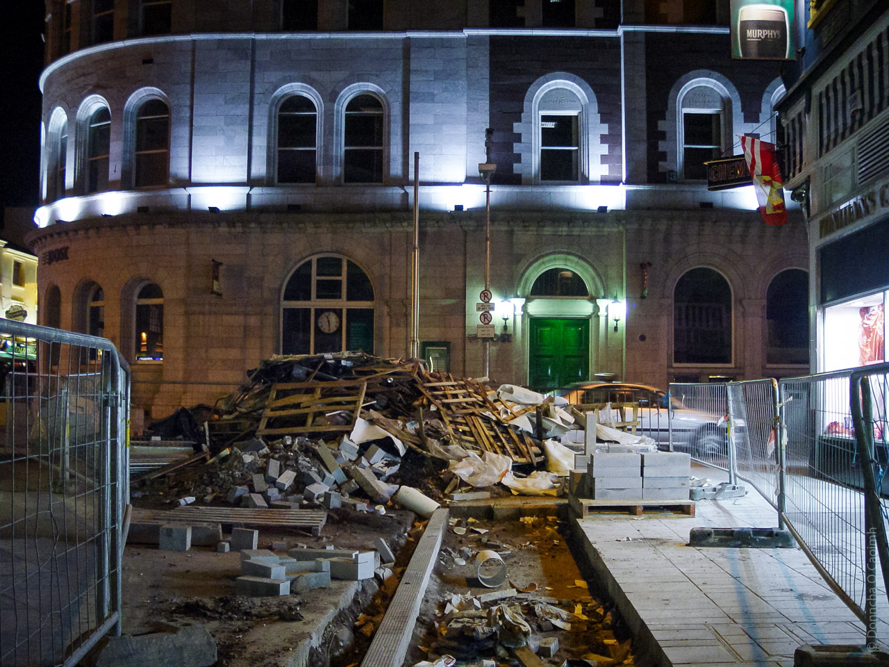 A construction site in a city, with the middle of a paved road dug up.