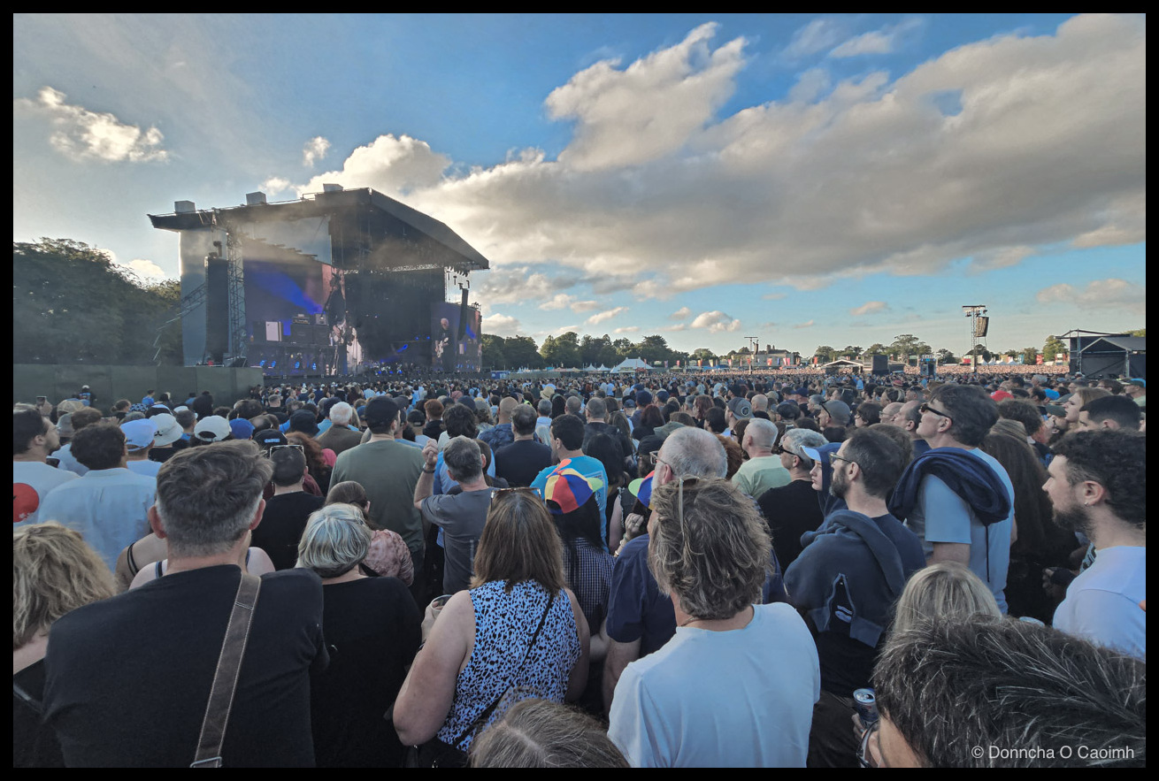 A wide angle photo of people watching the stage, with the crowd extending all the way to the to background.